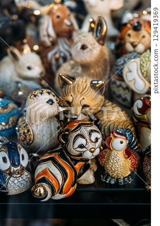 Colorful ceramic animal figurines are displayed behind glass in a storefront window. Collectibles market, nostalgia design, memory-based marketing, curated collections 129419369
