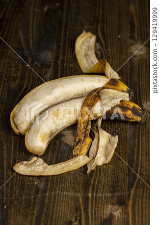 banana on a black pine wood table closeup, blackening old ripe banana whose color changes from yellow to black 129419999