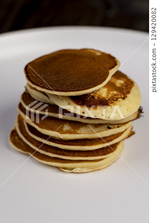 pancakes stacked together on a white bowl, a tower of small milk pancakes on a bowl, side view pancakes stacked together on a white bowl, a tower of small milk pancakes on a bowl, side view 129420082