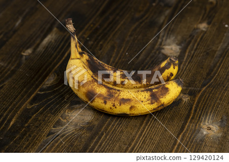 banana blackened during storage on a black board, blackened rotting banana on a wooden table banana blackened during storage on a black board, blackened rotting banana on a wooden table 129420124