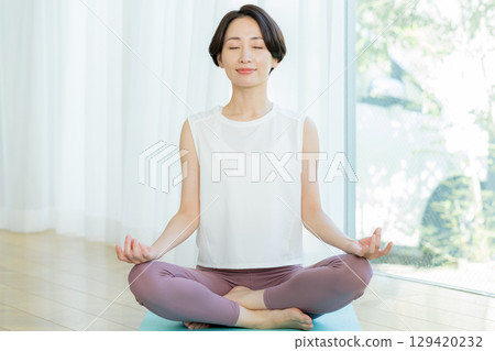Woman doing yoga in the living room Woman doing yoga in the living room 129420232