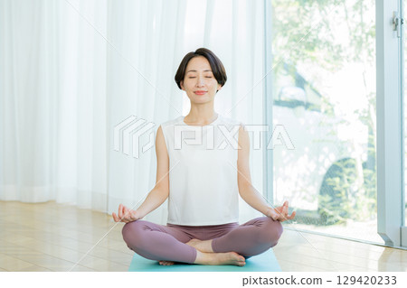 Woman doing yoga in the living room Woman doing yoga in the living room 129420233