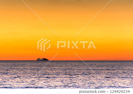 Cruise ship and sunset on the horizon 129420234