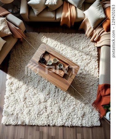Overhead view of a cozy living room setup with a wooden coffee table and fluffy rug 129420263