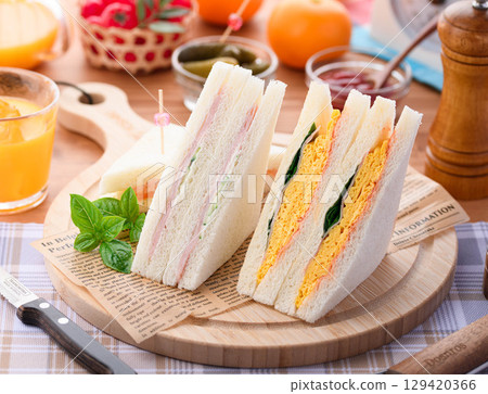 A mixed sandwich and orange juice perfect for breakfast or lunch, presented in a stylish cafe-style setting. 129420366
