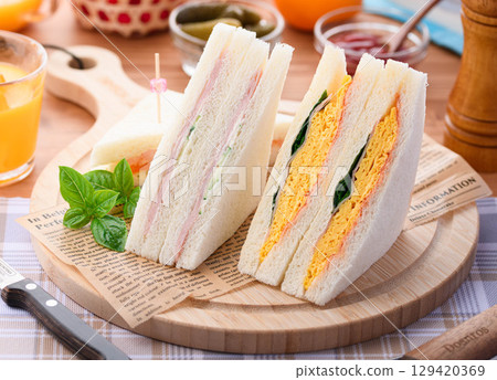 混合三明治和柳橙汁是完美的早餐或午餐,在時尚的咖啡館風格環境中呈現。 混合三明治和柳橙汁是完美的早餐或午餐,在時尚的咖啡館風格環境中呈現。 129420369