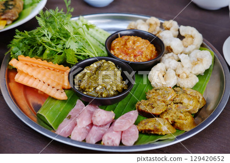 Northern Thai spicy green chilli dip with sausage and crackling with vegetable set on banana leaf is traditional Thai food 129420652