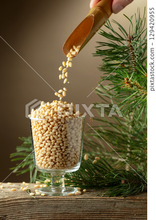 Pine nuts is poured in a glass bowl. Pine nuts is poured in a glass bowl. 129420955