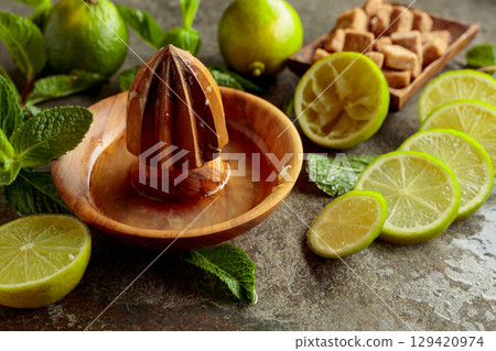 Wooden citrus squeezer and ingredients for making summer refreshing drinks. 129420974