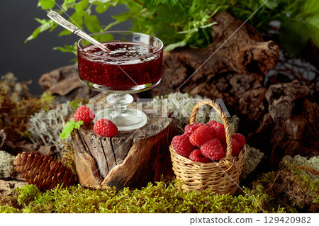 Raspberry jam with fresh berries in small basket in the forest. 129420982