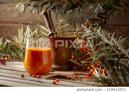 Glass of sea buckthorn juice with branches and fresh berries. Glass of sea buckthorn juice with branches and fresh berries. 129421051