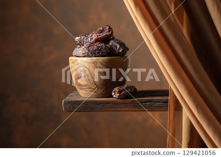 Dried medjool dates in wooden dish on a brown background. Dried medjool dates in wooden dish on a brown background. 129421056