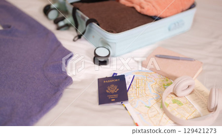Traveler plans vacation adventure packing suitcase with passport map headphones for exciting international trip abroad 129421273