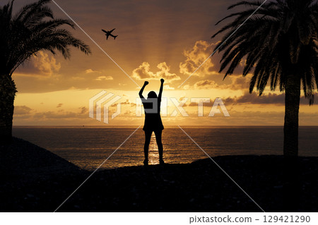 Joyful Silhouette of Woman at Tropical Sunset. Freedom and Summer Vibes 129421290