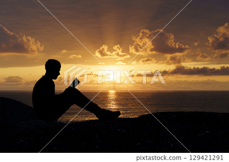 Man Reading a Book at Sunset. Knowledge and Reflection 129421291