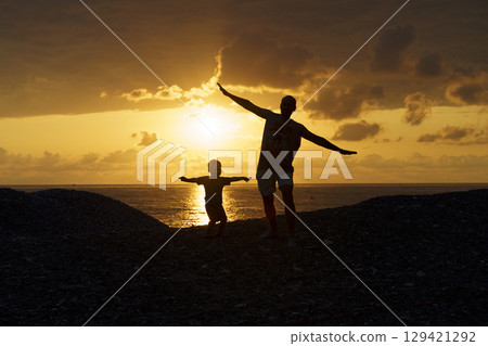 Father and Son Silhouettes at Sunset. Family Bonding Moment 129421292