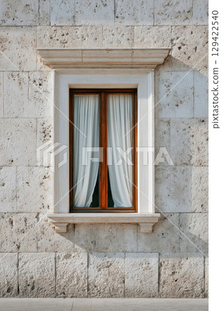 Wooden framed window with white curtains on stone wall 129422540
