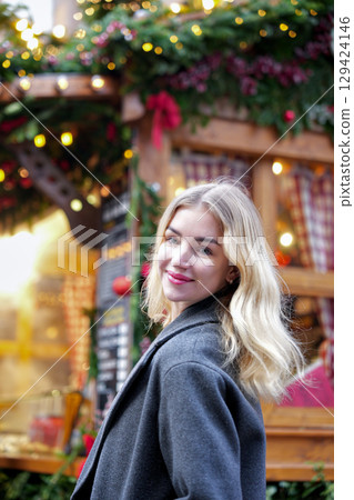 Blonde woman smiling at Christmas market in festive city lights 129424146