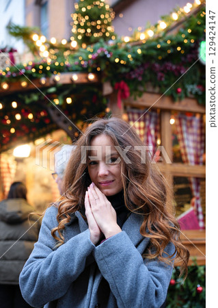 Woman in winter coat at Christmas market with lights 129424147