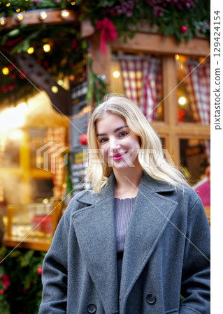 Blonde woman in gray coat at festive Christmas market Blonde woman in gray coat at festive Christmas market 129424154