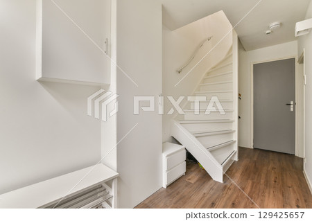 A sleek and bright hallway featuring modern architecture, clean lines, and minimalist decor. The well-lit space has a stylish staircase and functional storage units. A sleek and bright hallway featuring modern architecture, clean lines, and minimalist decor. The well-lit space has a stylish staircase and functional storage units. 129425657