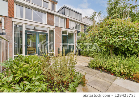 A contemporary home surrounded by vibrant gardens and pathways, showcasing the beauty of modern landscaping and outdoor living spaces. A contemporary home surrounded by vibrant gardens and pathways, showcasing the beauty of modern landscaping and outdoor living spaces. 129425755