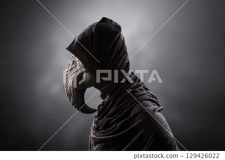 Creepy figure with long bird beak mask in hooded cloak at night over dark misty background Creepy figure with long bird beak mask in hooded cloak at night over dark misty background 129426022