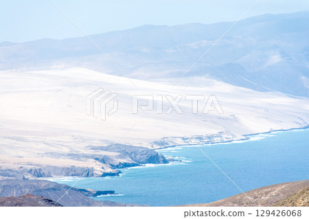 一座荒涼、乾燥、光禿禿的山峰在明媚的陽光下熠熠生輝，遠處的大海清晰可見。富埃特文圖拉島內陸 129426068