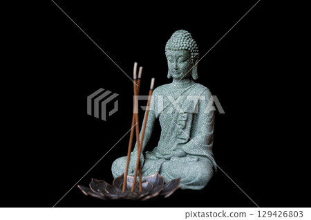 buddha statue with incense sticks on black background 129426803