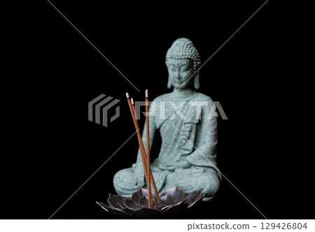 buddha statue with incense sticks on black background 129426804