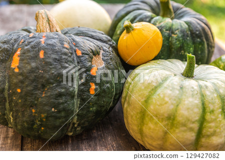 Autumnal Background. Natural autumn fall view pumpkins on wooden background. Inspirational october or september wallpaper. Change of seasons ripe organic food concept. Halloween party Thanksgiving day Autumnal Background. Natural autumn fall view pumpkins on wooden background. Inspirational october or september wallpaper. Change of seasons ripe organic food concept. Halloween party Thanksgiving day 129427082