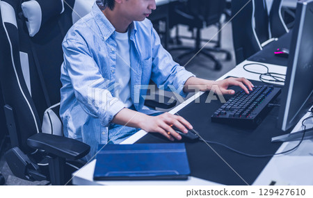 Male student playing on a gaming PC 129427610
