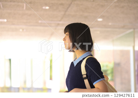 Profile of a female university student wearing a backpack walking around the campus Profile of a female university student wearing a backpack walking around the campus 129427611