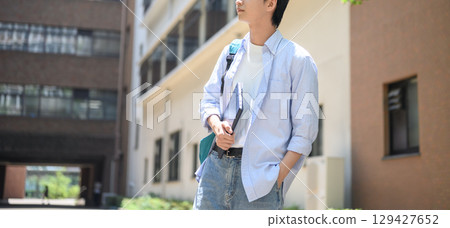 Long shot of a male college student walking on campus Long shot of a male college student walking on campus 129427652