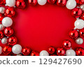 New year frame of white and red round Christmas balls, red festive background with decorative decoration and place for text 129427690
