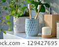 Two toothbrush with natural bristles in blue holder and other toiletries in bright bathroom setting during morning light 129427695