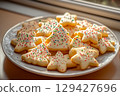 Festive decorated baked christmas cookies on white plate on windowsill near sunny window during the holiday season 129427696