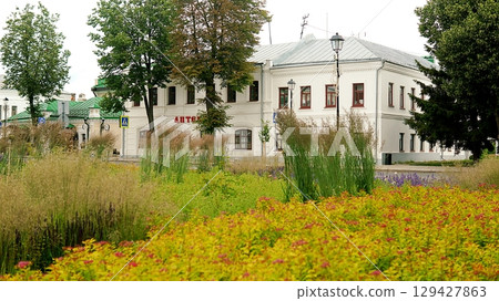 Beautiful yellow building and red, yellow and green wildflowers. 129427863