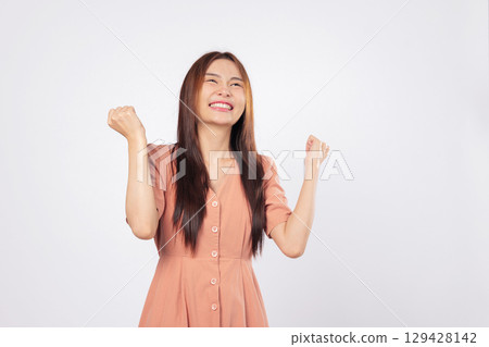 Success in her eyes and success in her pose the woman is excited smiling and raising fists expressing confidence isolated studio white background business profile style 129428142
