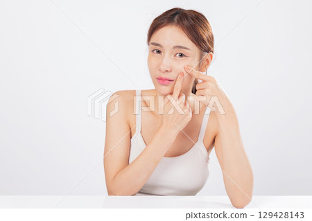 Acne appears around her forehead while acne near her nose adds to the concern, as she carefully squeezes spots and addresses skin care with honesty and self-awareness. isolated studio white background Acne appears around her forehead while acne near her nose adds to the concern, as she carefully squeezes spots and addresses skin care with honesty and self-awareness. isolated studio white background 129428143