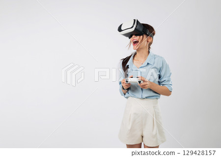 Game entertainment begins as Excited young woman explores a new VR game world, fully engaged in virtual reality with console. isolated studio white background 129428157