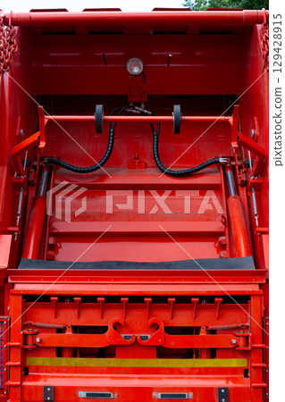 Close-up of the rear mechanism of a garbage truck designed to lift and empty waste containers. The hydraulic system with hooks and rollers is used for efficient trash collection and disposal Close-up of the rear mechanism of a garbage truck designed to lift and empty waste containers. The hydraulic system with hooks and rollers is used for efficient trash collection and disposal 129428915