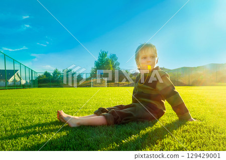 The child goes in for sports at the stadium. The boy training before playing football. 129429001