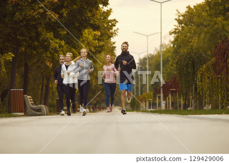 Happy young sport group of people jumping standing in a circle with hands up in nature. 129429006