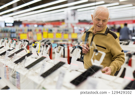 elderly man examines smart watch in showroom of electronics store elderly man examines smart watch in showroom of electronics store 129429102