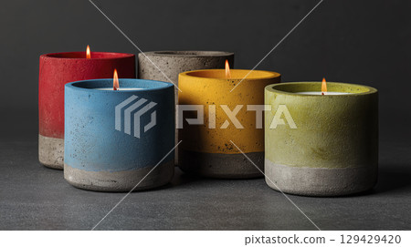 Colorful concrete candles with lit flames arranged dark surface creating cozy and modern ambiance showcasing vibrant hues of red blue yellow gray and green perfect for home decor or special 129429420