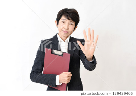一位身著西裝的中年婦女擺出停止姿勢 一位身著西裝的中年婦女擺出停止姿勢 129429466