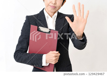 A middle-aged woman in a suit making a stop pose 129429467