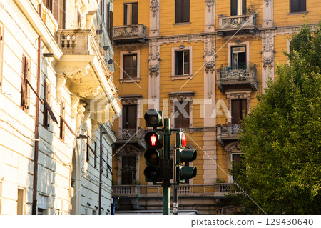 Pedestrian traffic light. Red signal color - prohibition of crossing for pedestrians. Yellow houses buildings. La Spezia Italian city. Architecture traffic, Italy. 129430640