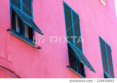 Green shutters on the windows. Pink houses buildings Italian village architecture Italy. 129430665